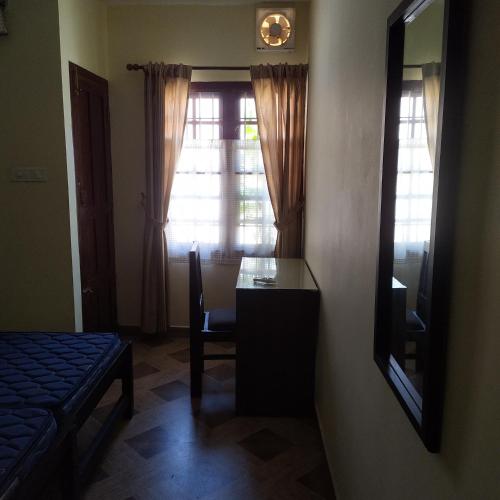a bedroom with a desk and a mirror and a window at Sundance Beach Villa on Princess Street in Cochin