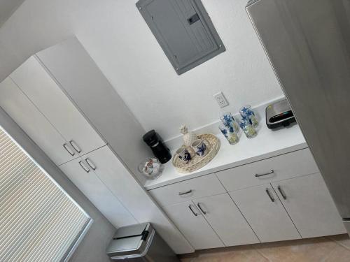 een badkamer met witte kasten, een wastafel en een spiegel bij Hostel Beds & Sheets FLL AIRPORT in Dania Beach