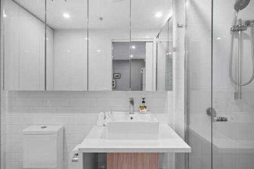 y baño blanco con lavabo y ducha. en Boutique Park-view 1BR Apartment, Central location en Brisbane