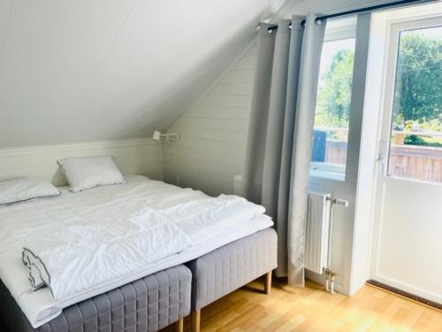 Cama blanca en habitación con ventana en Bryggvingens Apartment 1 en Nösund