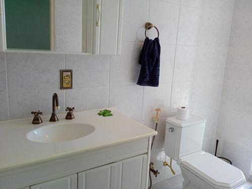 a white bathroom with a sink and a toilet at Apartamento A 43 Flat Centro in Mogi das Cruzes
