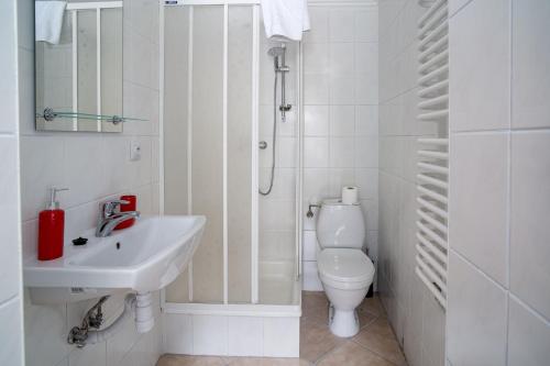 a white bathroom with a sink and a toilet at VacationClub - Ski Lodge Szczyrk Pokój 6 in Szczyrk