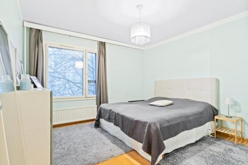 a white bedroom with a bed and a window at 2 room apartment in Pasila in Helsinki