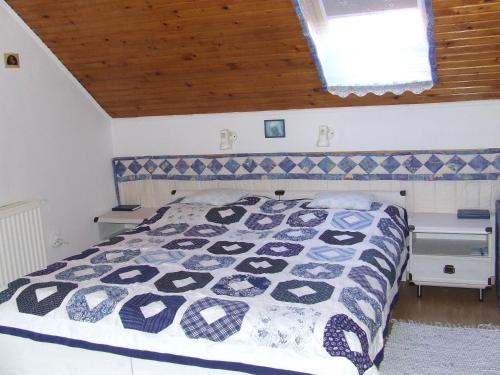 ein Schlafzimmer mit einem Bett mit einer blau-weißen Decke in der Unterkunft Czanek Apartman in Komárom