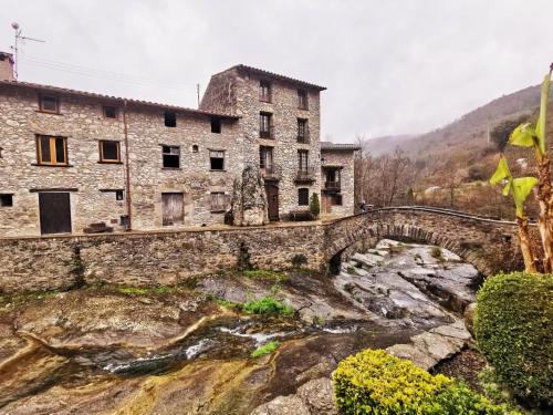 a stone building and a bridge over a river at 4LLARS in Beget