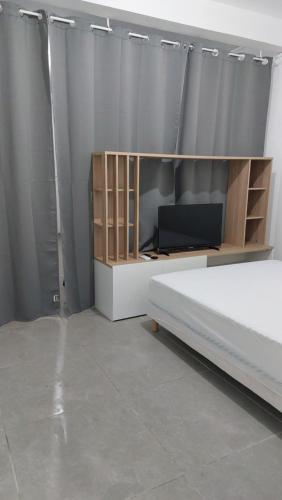 um quarto com uma cama e uma televisão numa prateleira em Lafleur_doré Studio em Le Vauclin