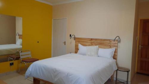 a bedroom with a large white bed and two chairs at Steps Accommodation in Gobabis