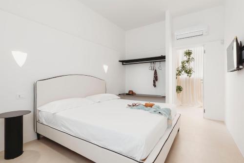 ein weißes Schlafzimmer mit einem weißen Bett und einem Tisch in der Unterkunft Marhaba in Torre Pali 