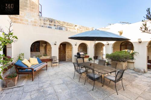 a patio with a table and chairs and an umbrella at A stunning, townhouse with magnificent pool area by 360 Estates in Żebbuġ