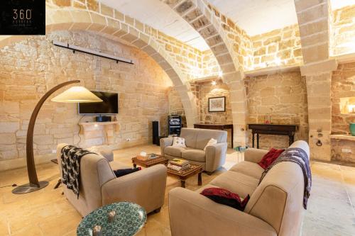 a living room with couches and a stone wall at A stunning, townhouse with magnificent pool area by 360 Estates in Żebbuġ
