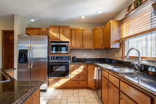 a kitchen with wooden cabinets and a stainless steel refrigerator at Misty Lake Hot Tub w Lake Access in Oak Ridge