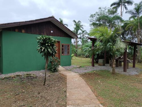 a green building with a tree in front of it at Pousada Serra Verde Ecolodges in Morretes