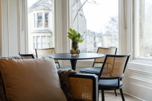 a table and chairs in a room with a window at The West End Retreat - Your Luxurious 5* Apartment in Glasgow