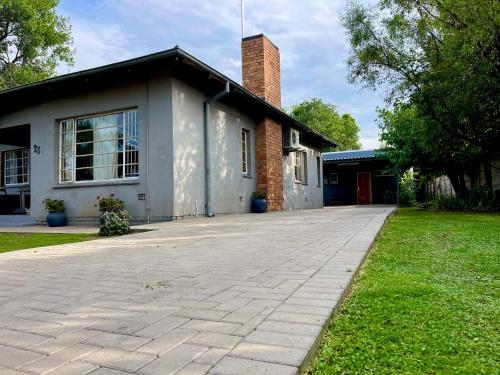 a house with a brick chimney and a driveway at Wamelia Guesthouse in Bloemfontein