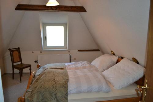 1 dormitorio con 1 cama con ventana y silla en Doktors Hus, en Oldenswort