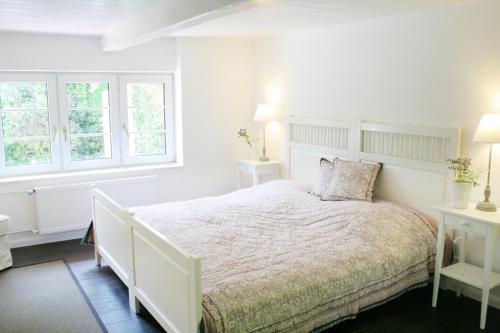 a white bedroom with a bed and two windows at Krabbe 32 in Tetenbüll