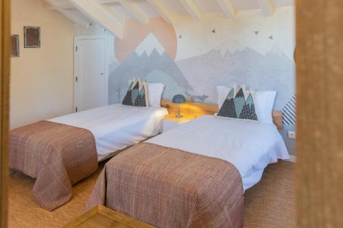 a bedroom with two beds and a mural of mountains at Chão do Rio - Turismo de Aldeia in Seia