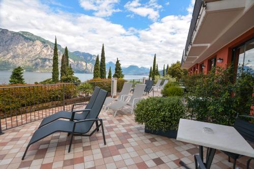 a patio with chairs and a view of the water at Hotel Oasi Beach in Malcesine