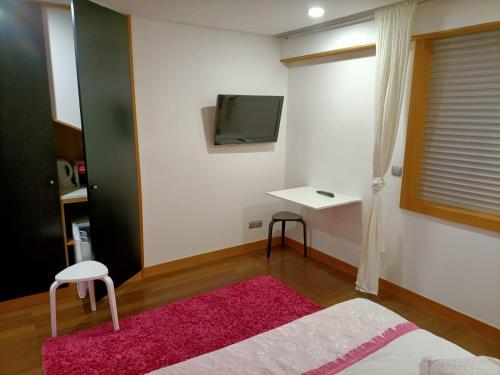 um quarto com um tapete rosa e uma televisão na parede em O Cantinho do Arnaldo em Viana do Castelo