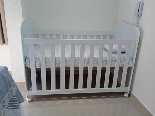 a white crib sitting in a corner of a room at Apartamento completo A42 Flat Centro in Mogi das Cruzes