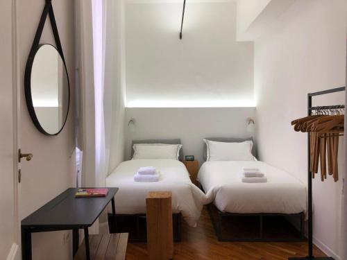 twee bedden in een kamer met een spiegel en een tafel bij Art Apartments in Florence