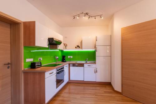 a kitchen with green walls and white cabinets at Ferienwohnung s'Kammerl in Wolfegg