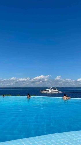 a swimming pool with a cruise ship in the water at Tropical Executive Hotel Flats in Manaus