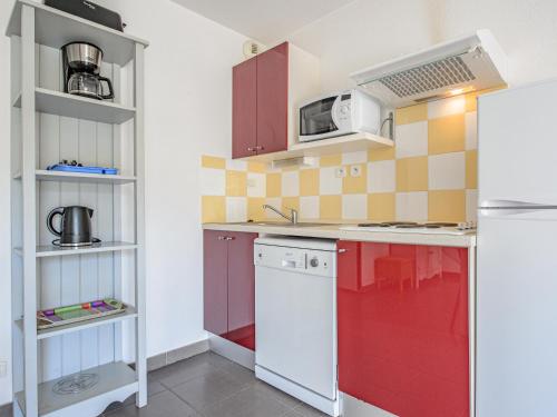 a kitchen with red cabinets and a white refrigerator at Vacanceole - Residence les Demeures du Ventoux in Aubignan