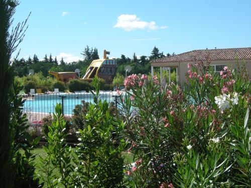 a swimming pool with flowers in front of a house at Vacanceole - Residence les Demeures du Ventoux in Aubignan