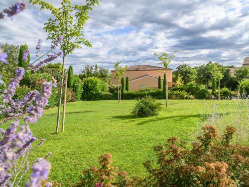 a garden with purple flowers and a house in the background at Vacanceole - Residence les Demeures du Ventoux in Aubignan