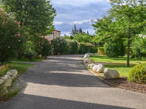 a path in a garden with flowers and trees at Vacanceole - Residence les Demeures du Ventoux in Aubignan