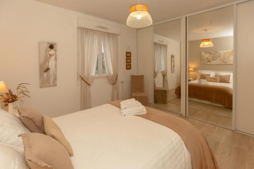 Habitación blanca con 2 camas y espejo. en Atlantic Selection - Un séjour à la Villa Sharon avec terrasse et parking, en Capbreton