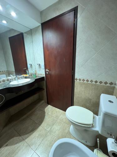 a bathroom with a toilet and a sink and a wooden door at Complejo Aires 1 in San Bernardo