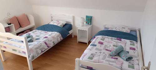 - une chambre avec 2 lits, une table et un lit bébé dans l'établissement Escale Côte et Mer, à Clohars-Fouesnant