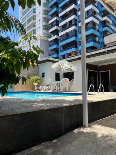 a swimming pool with chairs and an umbrella next to a building at casa aconchegante com lazer completo in Praia Grande