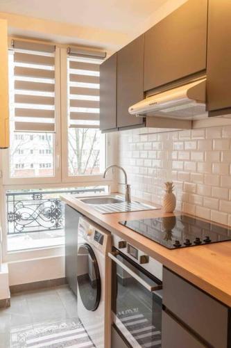 une cuisine avec un évier et une cuisinière four supérieur dans l'établissement Le Parisien-Clichy-2 pièces Zen, à Clichy