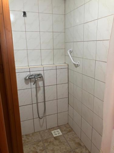 een douche met een slang in een wit betegelde badkamer bij Tuja Vendégház in Lajoskomárom