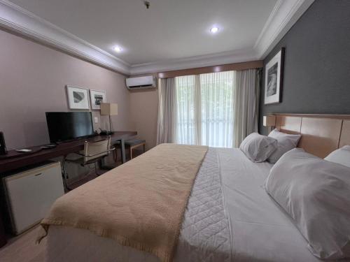 um quarto de hotel com uma cama grande e uma secretária em LOBIE BARRA DA TIJUCA MEDITERRÂNEO no Rio de Janeiro