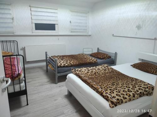 Habitación con 3 camas con sábanas de leopardo en Kaya Ferienwohnungen, en Plettenberg