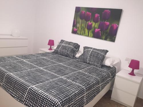 1 dormitorio con 1 cama en blanco y negro con tulipanes morados en Apartamento Centro Historico Teruel, en Teruel