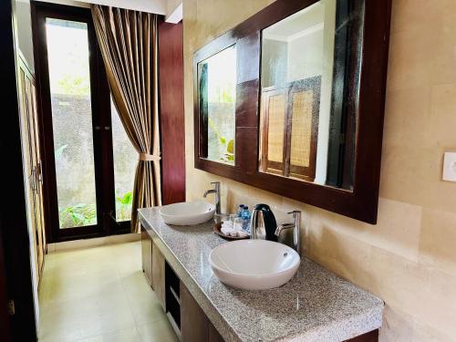 a bathroom with two sinks on a counter with windows at Wana Karsa The Villas Ubud in Ubud