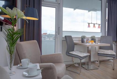 d'un salon avec une table, des chaises et une fenêtre. dans l'établissement Ferienwohnung mitten in Westerland mit Balkon, à Westerland