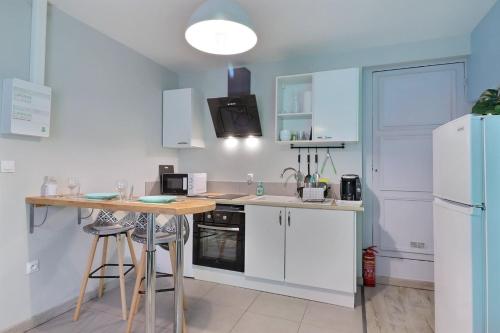 - une cuisine avec des placards blancs, une table et un réfrigérateur dans l'établissement Appart du Pont Vert B01 ~ proche centre Mon Groom, à Troyes