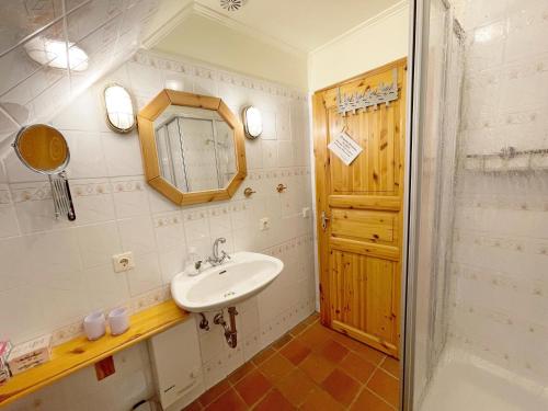 uma casa de banho com um lavatório, um espelho e um chuveiro em Hooger Wal 19 Morsumer Kliff em Morsum