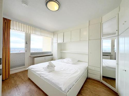 ein weißes Schlafzimmer mit einem Bett und zwei Fenstern in der Unterkunft Haus Metropol App 327 mit Meerblick und Cityblick 3 Balkone in Westerland