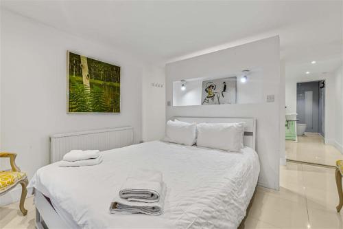 a white bedroom with a large white bed with towels on it at Earls Court Spacious Apartment in London