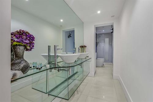 a bathroom with two sinks and a vase of flowers at Earls Court Spacious Apartment in London