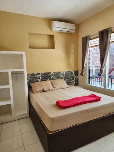 Un dormitorio con una cama con una manta roja. en Penginapan PIP Semarang en Jomblang