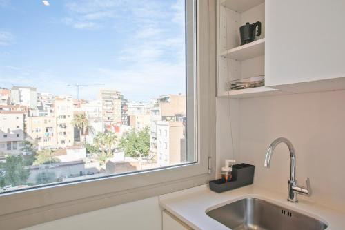 fregadero de cocina y ventana con vistas a la ciudad en BcnStop Sant Pau Suites, en Barcelona