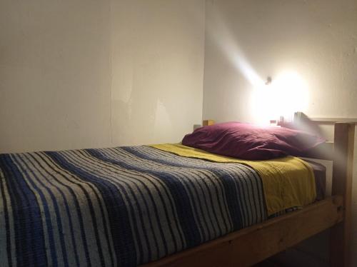 a bed with a striped blanket and a light on the wall at Origenes in Santiago